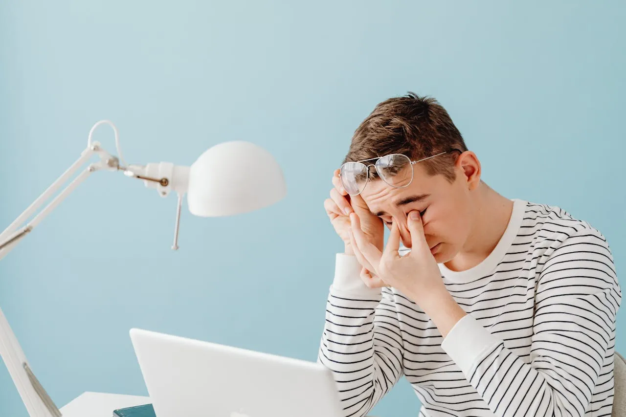 Tired man rubbing his eyes while working on a laptop